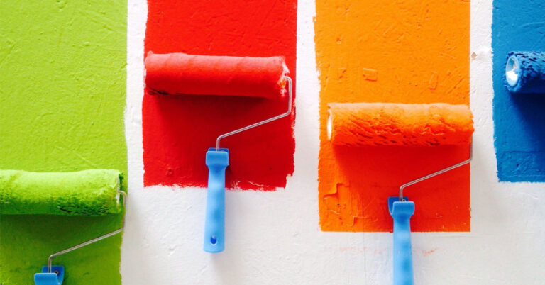 Paint rollers of different colors on wall