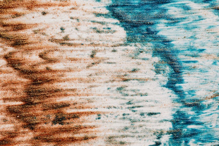 Abstract textured surface made of colorful paints of blue and brown colors on white background